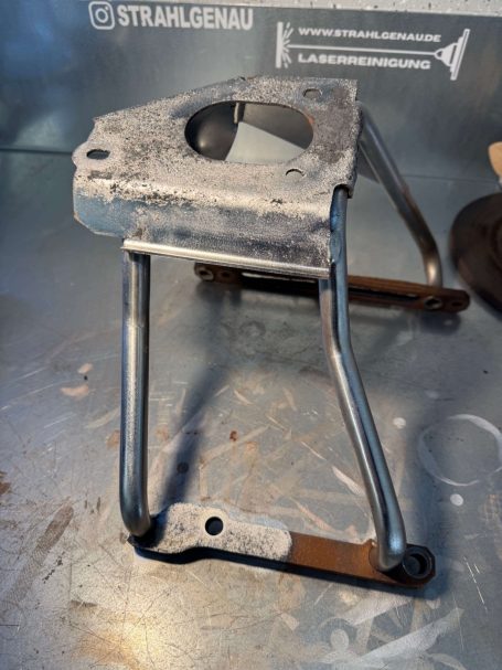 Grau lackierter Metallständer mit zwei Stützbeinen und kreisförmiger Aussparung.