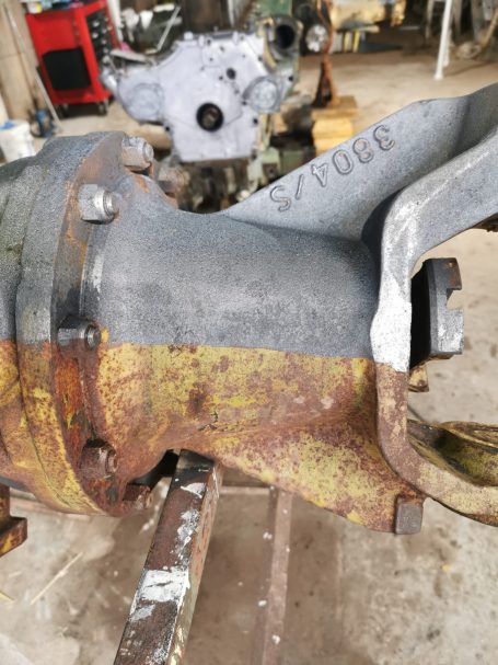 Rostige Maschinenkomponente mit grauem und gelbem Finish in einer Werkstatt.