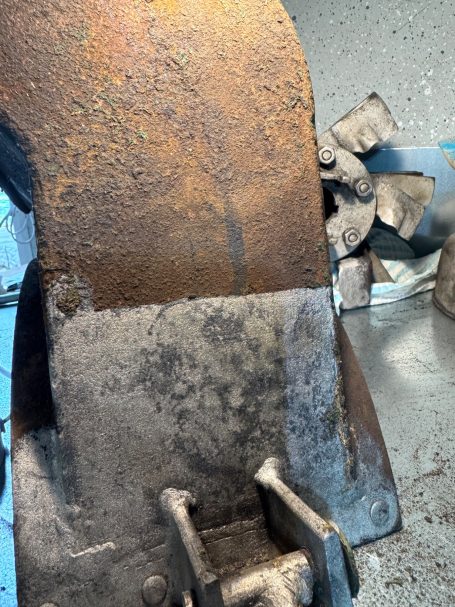 Rostige Metalloberfläche mit einer beschädigten Textur und einigen kleinen Metallstücken im Hintergrund.